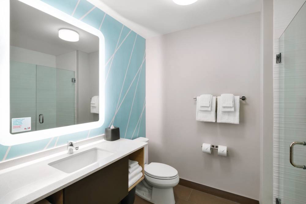 A bright bathroom with a large backlit mirror